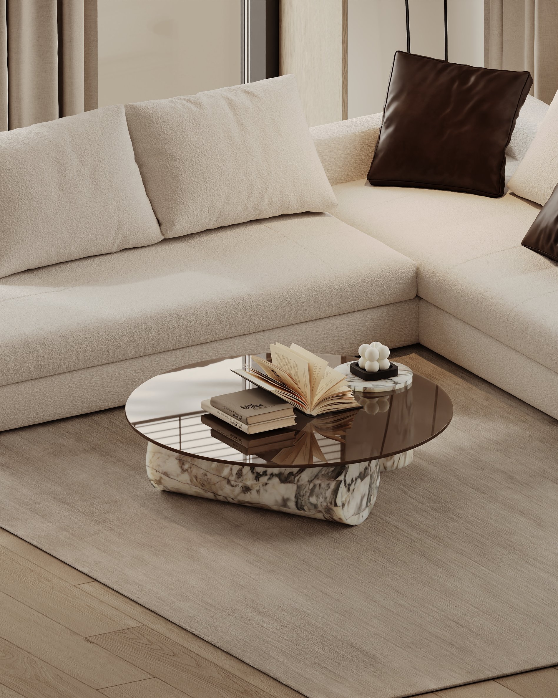 Detail of marble coffee table with books and decor, placed on a neutral rug beside a cream sectional sofa.