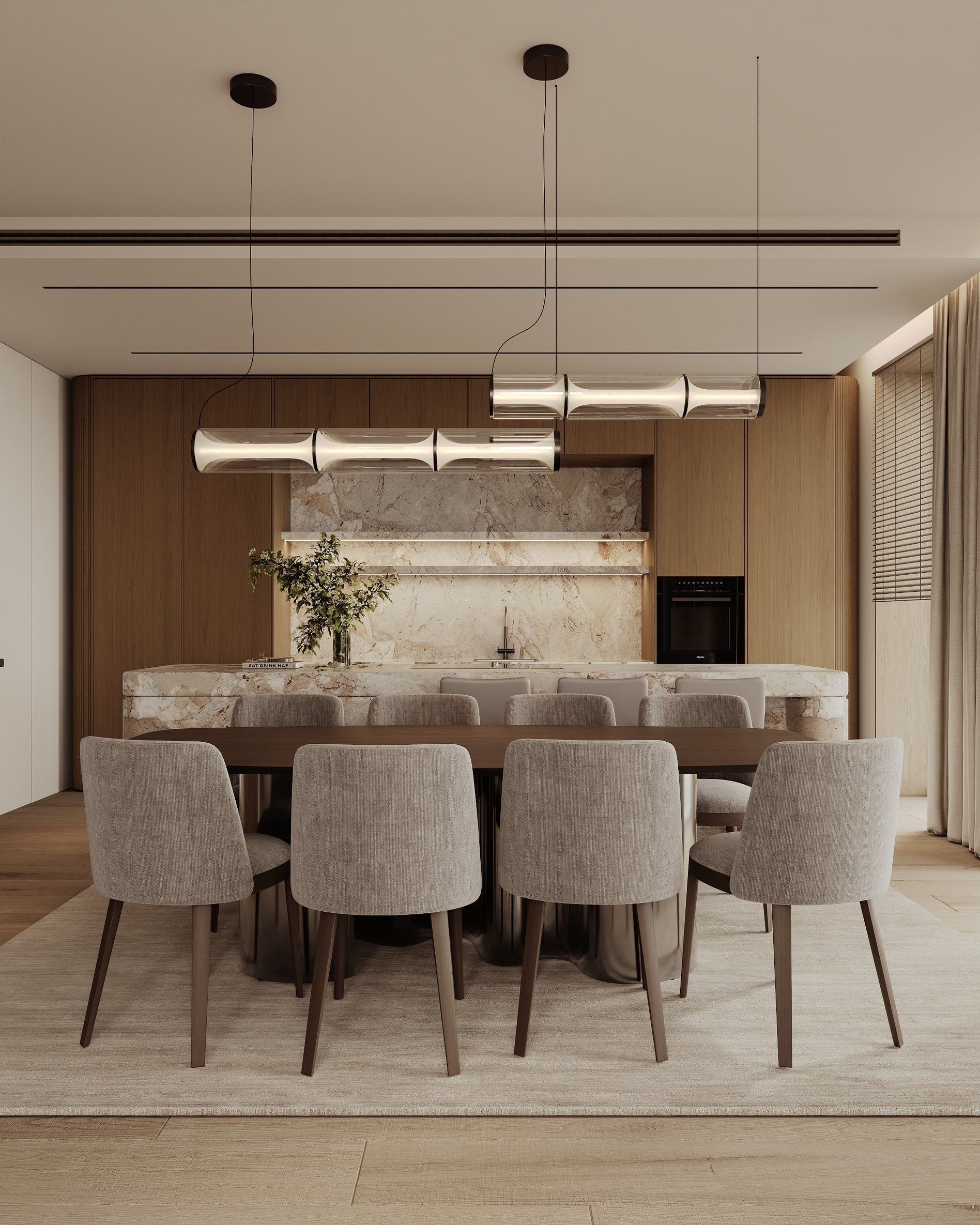 Dining table with soft upholstered chairs and sculptural pendant lights, set before a marble kitchen backdrop.