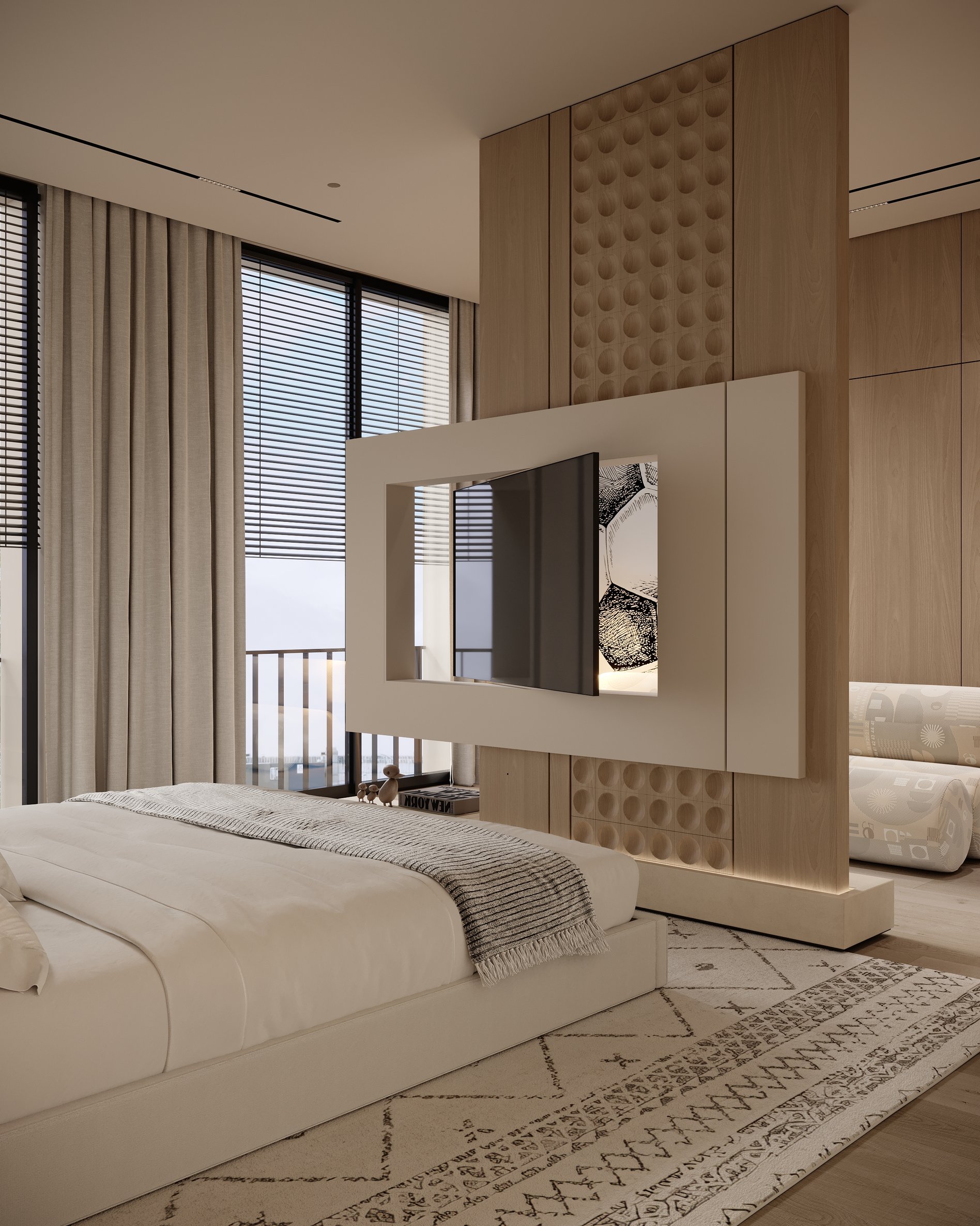 Bedroom with floating TV divider, upholstered bed, and patterned rug, with natural light from large windows.
