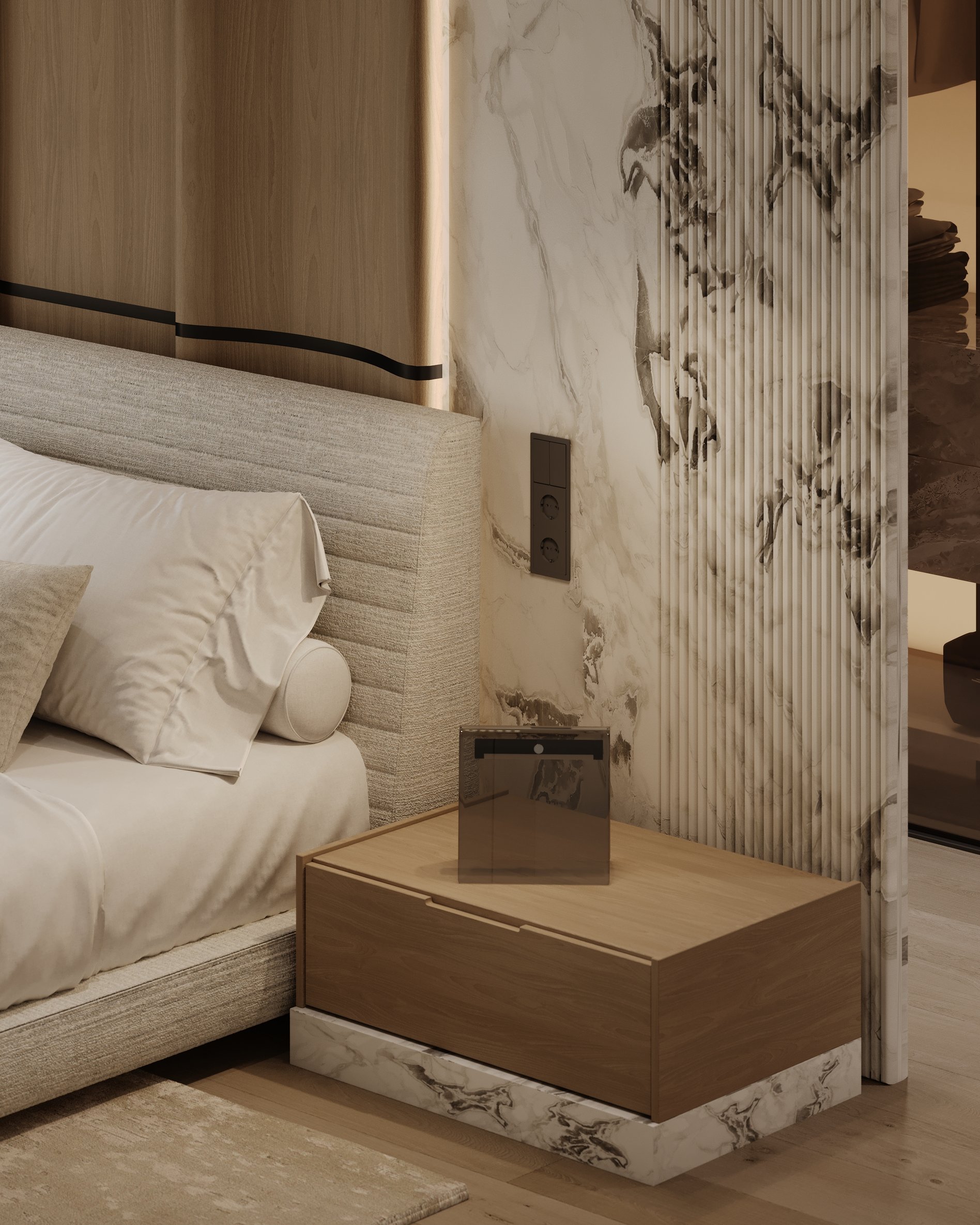Detail of nightstand with wood and marble base, set against a marble accent wall with integrated lighting.