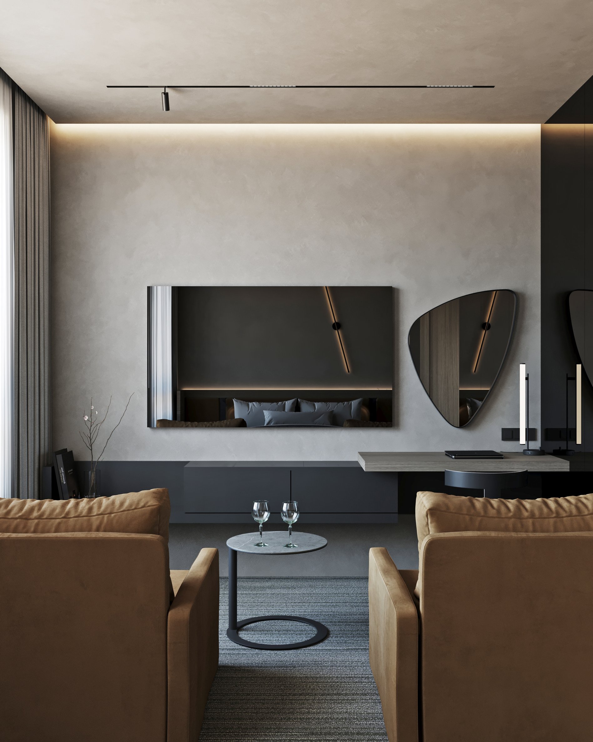 Hotel room living area with tan leather armchairs, decorative mirror, and wall-mounted TV unit.