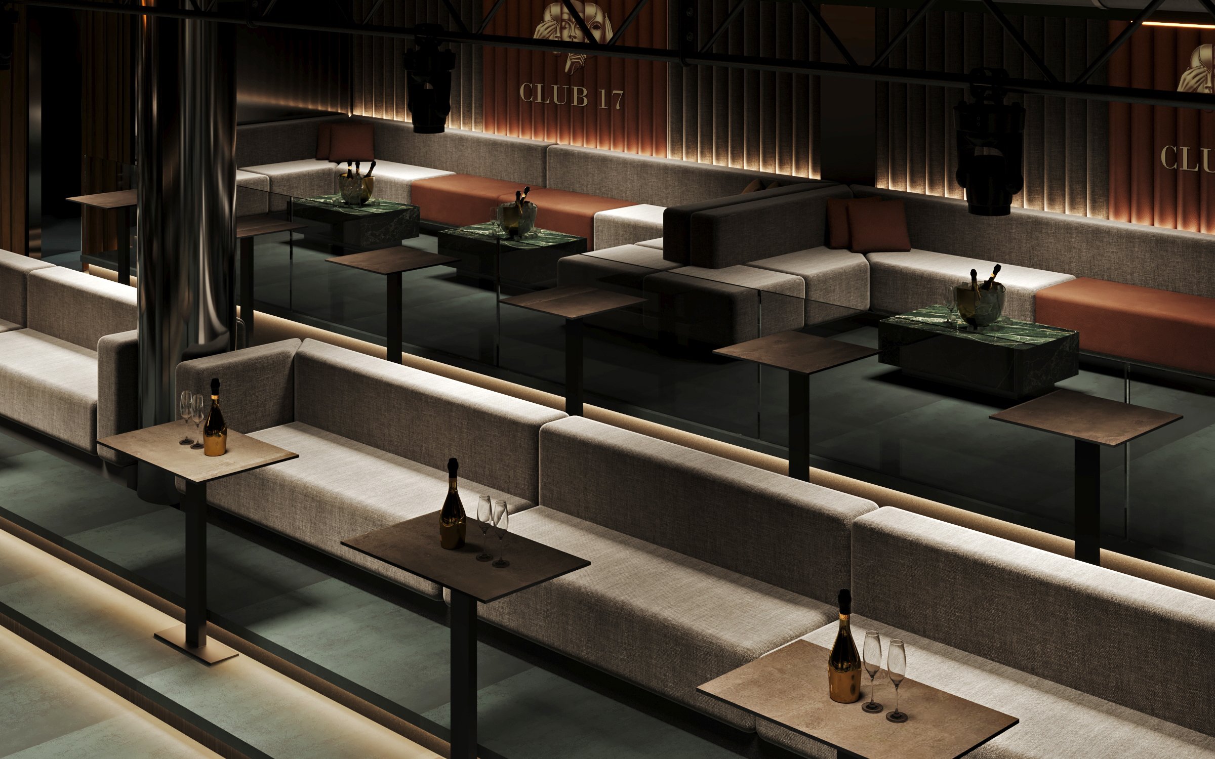 Luxurious seating area featuring grey upholstered banquettes, bronze tables, and ambient lighting with Club 17 branding on textured wall panels.